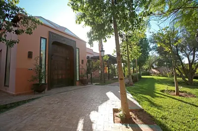 a building with a brick driveway next to a tree at Domaine DAR JMEL & Dar Abi Samama in Marrakech