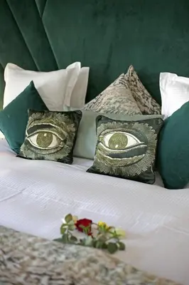 a bed with green and white pillows with eyes on it at Domaine DAR JMEL & Dar Abi Samama in Marrakech
