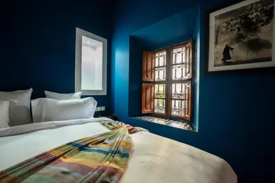 a blue room with a bed and a window at Riad Les Yeux Bleus in Marrakech