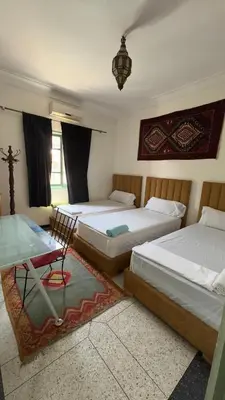 a bedroom with two beds and a table and a desk at Dar el Koutoubia in Marrakech