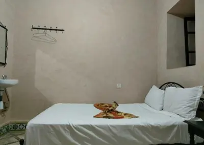 a bedroom with a white bed with a plate on it at Hotel Zagora in Marrakech