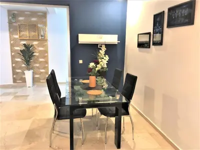 a dining room with a glass table and black chairs at SUPER APPART Marrakech - Confort Propreté Proximité in Marrakech