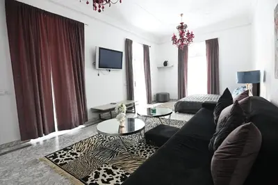 a living room with a black couch and a tv at Riad 5 Chambres & Piscine & Breakfast - Marrakech in Marrakech