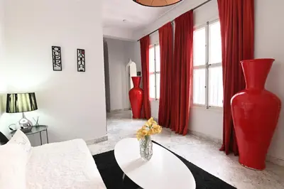 a living room with red curtains and a red vase at Riad 5 Chambres & Piscine & Breakfast - Marrakech in Marrakech