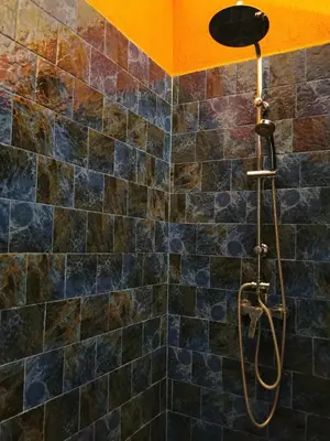 a shower in a bathroom with black tiles at Dar Al Hayat in Marrakech
