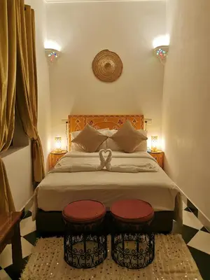 a bedroom with a large bed with two stools on it at Dar Al Hayat in Marrakech
