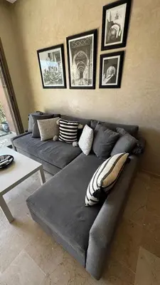 a living room with a gray couch and pictures on the wall at Studio sur golfe et piscine in Marrakech