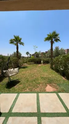 a park with a bench and two palm trees at Studio sur golfe et piscine in Marrakech