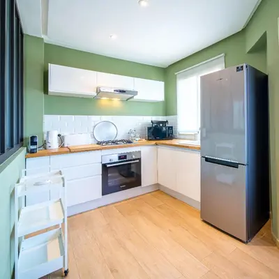 a kitchen with white cabinets and a stainless steel refrigerator at Perle Rare à Bab Ighli Marrakech in Marrakech