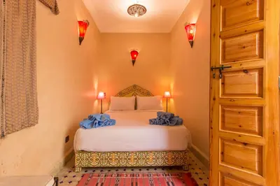 a bedroom with a bed with blue sheets and a door at Riad Colette EXCLUSIF - Médina - Breakfast - Wifi in Marrakech