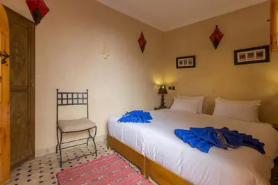 a bedroom with a bed with blue sheets and a chair at Riad Colette EXCLUSIF - Médina - Breakfast - Wifi in Marrakech