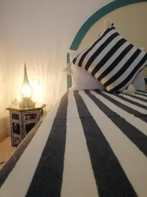 a bed with a black and white striped pillow and a lamp at Riad Dar Hamid Hotel & Spa in Marrakech