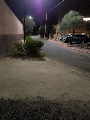 an empty street at night with a parking lot at MAISON de VACANCES in Marrakech