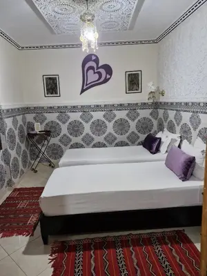 a bedroom with two beds and a purple heart on the wall at Riad De La Semaine in Marrakech
