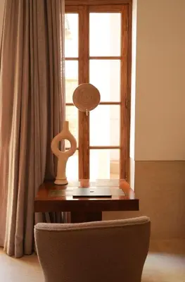 a table with a lamp and a chair in front of a window at Riad Kahena in Marrakech