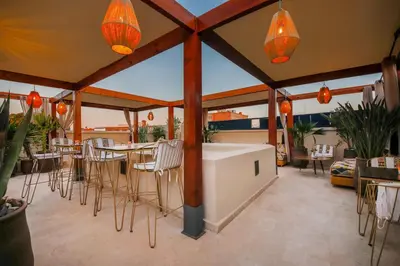 a patio with chairs and a bar on a roof at Riad Kahena in Marrakech