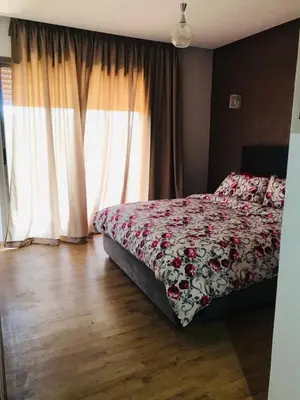 a bedroom with a bed with a floral bedspread and a window at SUNNY 48- Appart Cozy -Marrakech-centre in Marrakech