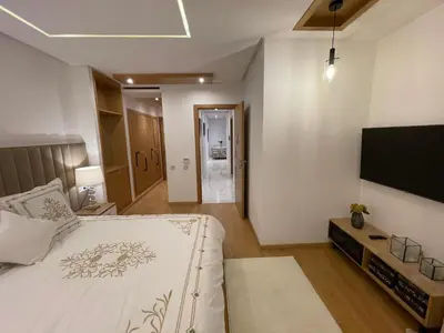 a bedroom with a large bed and a flat screen tv at NEW SUPER LUXURY APARTMENT (CENTRAL MARRAKECH) in Marrakech