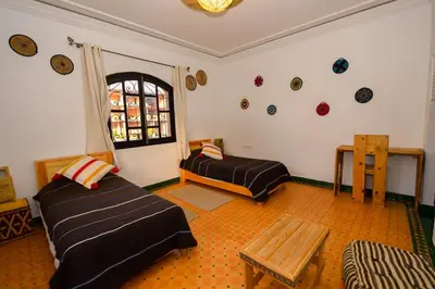 a room with two beds and a table and a window at Targafit Hotel & Hammam in Marrakech