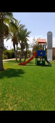 a playground with a slide in a park with palm trees at Atlas golf in Marrakech