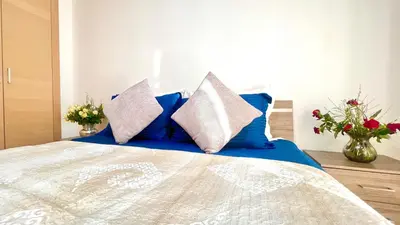 a bedroom with a bed with blue pillows and flowers at Prestigia Appartement de luxe in Marrakech
