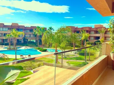 an apartment balcony with a swimming pool and palm trees at Prestigia Appartement de luxe in Marrakech