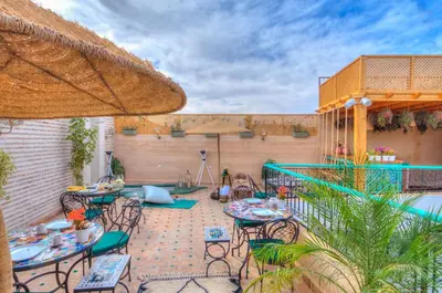 a patio with tables and chairs and an umbrella at riad paradis blanc in Marrakech