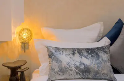 a bed with a pillow and a lamp and a table at riad paradis blanc in Marrakech