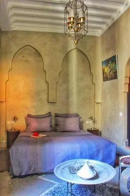 a bedroom with a large bed and a table at Riad Heva in Marrakech