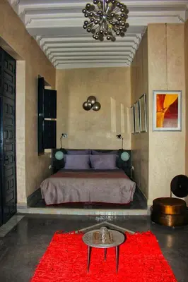 a bedroom with a large bed with a red rug at Riad Heva in Marrakech