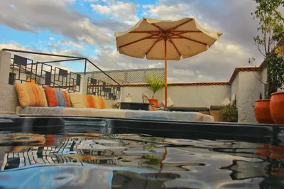 a pool with an umbrella and a couch and a table at Riad Heva in Marrakech