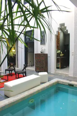 a pool with a couch and chairs next to a house at Riad Heva in Marrakech