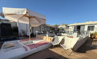 a patio with an umbrella and chairs and a bed at Riad Heva in Marrakech
