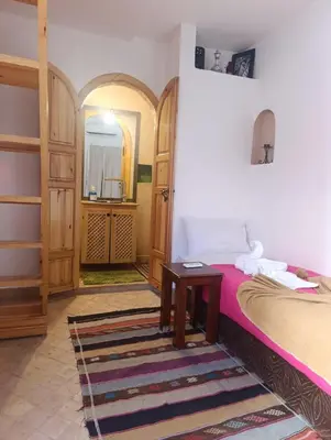 a bedroom with a bed and a table and a mirror at Riad Bonheur in Marrakech