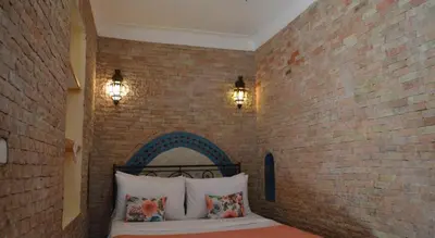 a bedroom with a brick wall and a bed with pillows at Riad Bonheur in Marrakech
