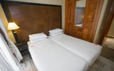 a bedroom with a large white bed and a lamp at Palmeraie Village in Marrakech