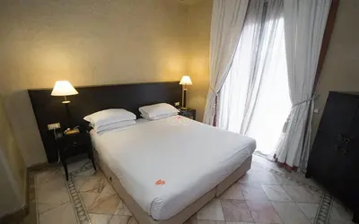 a large white bed in a room with a window at Palmeraie Village in Marrakech