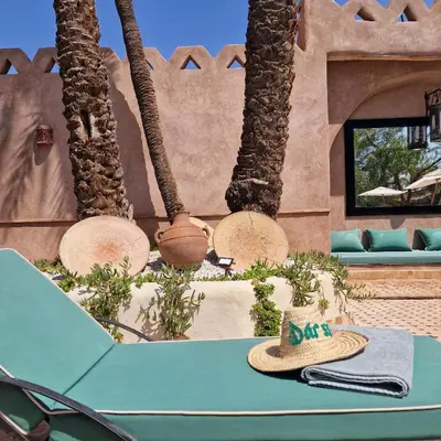a table with a hat on top of it next to palm trees at Hôtel Dar 55 - Berber House - Boutique Hôtel in Marrakech