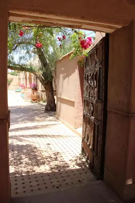 an open wooden door with flowers on a wall at Hôtel Dar 55 - Berber House - Boutique Hôtel in Marrakech