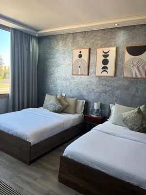 two beds in a room with paintings on the wall at Riad L'Aéroport in Marrakech