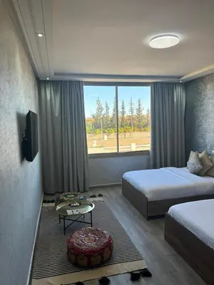 a bedroom with two beds and a table and a tv at Riad L'Aéroport in Marrakech