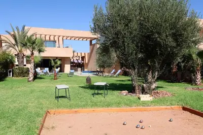 a building with a yard with a tree and a trampoline at Villa Firdaous in Marrakech