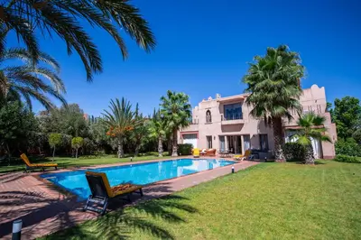 a villa with a swimming pool in front of a house at Villa Cartier in Marrakech