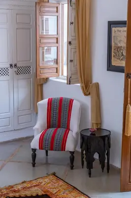 a white chair sitting in a room with a table at Riad Dar Talah in Marrakech