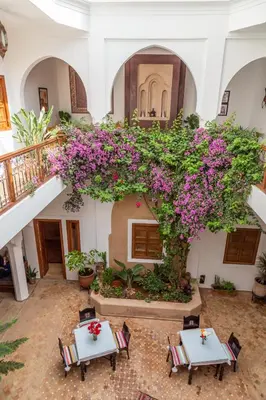 a courtyard with tables and flowers in a building at Riad Dar Talah in Marrakech