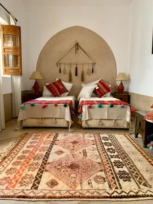 a bedroom with two beds and a rug at Riad Dar Talah in Marrakech