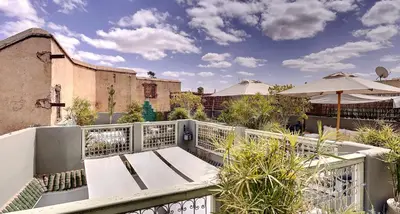 a balcony with a bench and an umbrella at Riad Dar Chacha in Marrakech