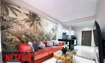 a living room with a red couch and a palm mural at The Best location to visit Marrakech Carré Eden a little Walk to the Médina in Marrakech