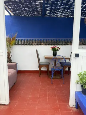 a patio with a table and chairs and a blue wall at Casa del Sol Marrakech in Marrakech