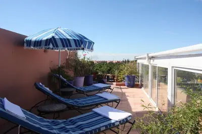 two chairs and an umbrella on a patio at Riad Basim in Marrakech